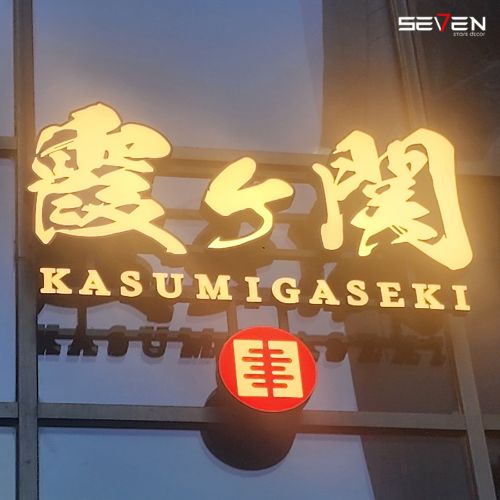 An illuminated commercial sign for 'KASUMIGASEKI' featuring large Japanese characters and English text below, with a red circular logo, showcasing Seven Star's commercial fit-out specialists in UAE branding design.