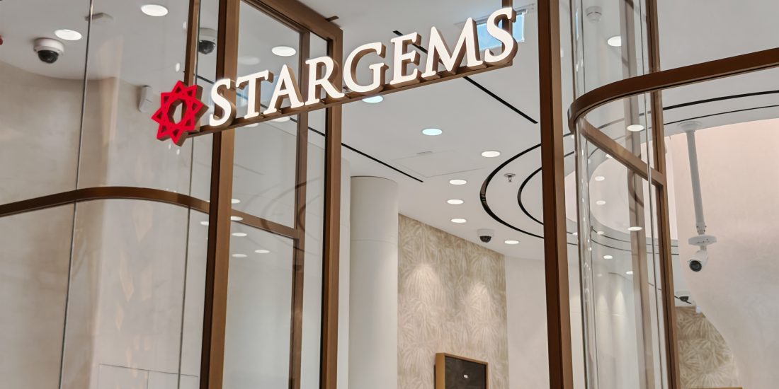 The sleek and modern entrance of 'STARGEMS' jewelry store, designed by Seven Star, featuring illuminated signage, curved glass, and luxurious interior glimpses, showcasing commercial fit-out specialists in UAE expertise.