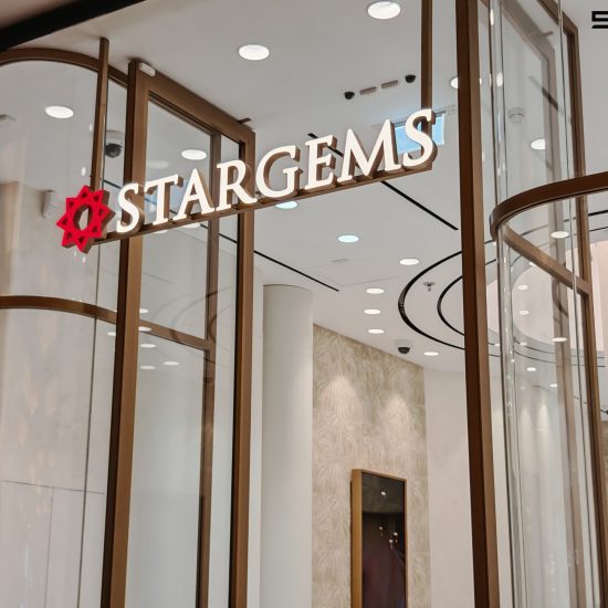 The sleek and modern entrance of 'STARGEMS' jewelry store, designed by Seven Star, featuring illuminated signage, curved glass, and luxurious interior glimpses, showcasing commercial fit-out specialists in UAE expertise.